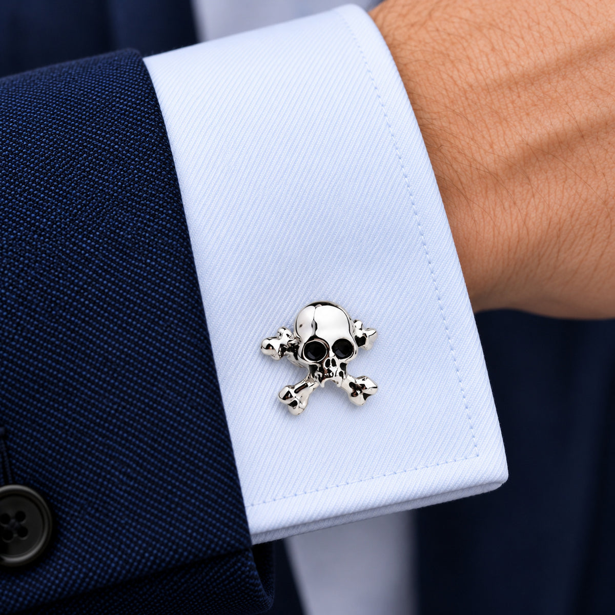 Gemelos Calaveras IV. Un gemelo en el puño azul claro de una camisa.